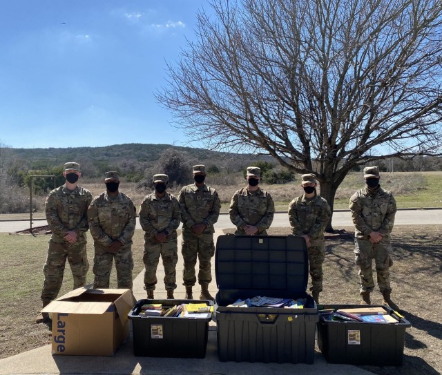 Soldiers with Bravo Company, 303rd Military Intelligence Battalion, 504th Military Intelligence Brigade pose for a photo with donated books, Feb. 23, 2021, Fort Hood, Texas. A duo consisting of a brother and sister organized the donation to raise awareness about mental health and suicide. (U.S. Army photo by Spc. Barry Philson)
