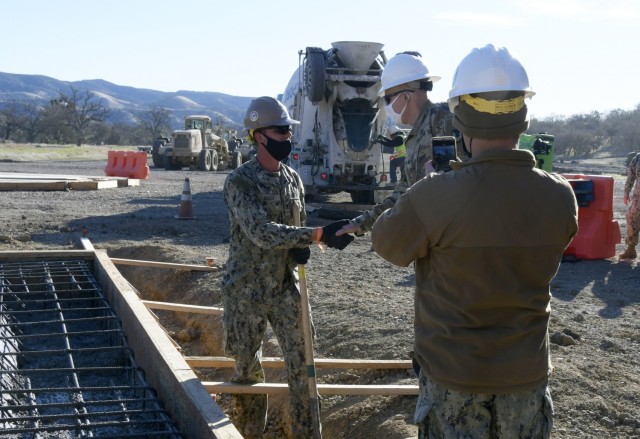 Naval Mobile Construction Battalion 5 based at Port Hueneme, California, constructed a concrete pad at Fort Hunter Liggett’s Training Area 10 during two weeks in February 2021. FHL Commander Col. Charles Bell presented four Seabees identified by the NMCB 6 officer-in-charge with a challenge coin for their exceptional service. Builder Petty Officer 3rd Class Gerou receives coin from Bell.