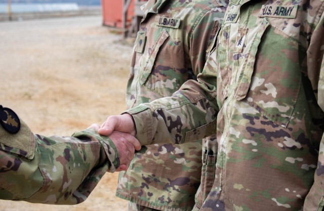 Col. Derek Adams, commander of Regional Command-East, Kosovo Force, presents a coin to Sgt. Spenser Sharp during a recognition ceremony at Camp Bondsteel, Kosovo, on March 8, 2021. Sharp, along with Spc. Cole Magnuson, demonstrated their dedication to selfless service by going out of the way to aid civilians during an emergency. (U.S. Army National Guard photo by Sgt. Jonathan Perdelwitz)