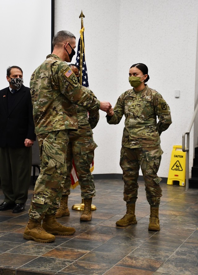 Brig. Gen. David S. Doyle, Joint Readiness Training Center and Fort Polk commanding general, presents a coin to Cpl. Samantha Corado, paralegal specialist, 317th Brigade Engineer Battalion, at the Office of the Staff Judge Advocate awards...