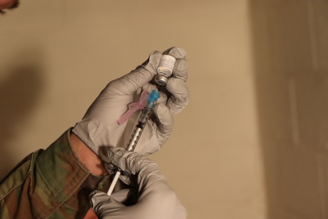 A William Beaumont Army Medical Center Soldier prepares a syringe with the Pfizer vaccine at Stayton Theater.