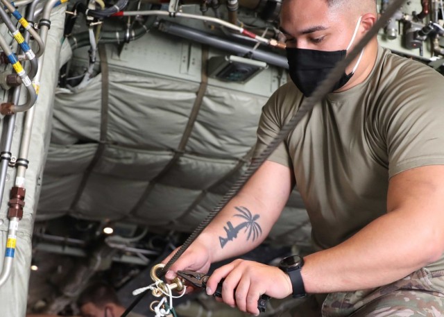 Army Spc. Christian Ramos, 151st Quartermaster Detachment, Fort Bragg, North Carolina, said he is a team leader for air drop system, equipment and repair. The Guam native said once the pallets were loaded onto the aircraft, he and the other riggers used strings and rubber bands to attach the parachutes to the static lines on both the left and right sides of the plane.  (U.S. Army photo by Staff Sgt. Neil McCabe)