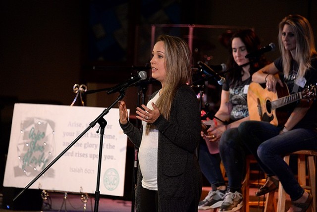 Protestant Women of the Chapel Retreat Coordinator Teresa Valencia encourages PWOC members to pray over how the Lord is leading them to shine in their community during the PWOC worship service, a follow-on to the morning's message delivered via...
