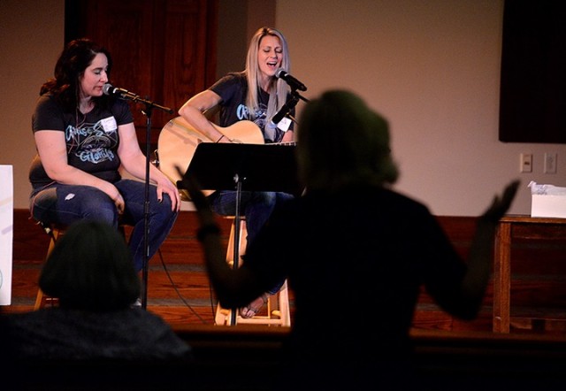 Caitlyn Mair, praise and worship leader for Protestant Women of the Chapel, and singer Kayla Atkins lead Diane Kohl and other PWOC members in singing "Battle Belongs" during the PWOC worship service, a follow-on to the morning's message delivered...