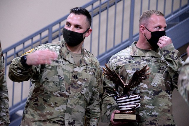 Capt. Micah Robbins, commander of Headquarters and Headquarters Company, Joint Regional Correctional Facility, 705th Military Police Battalion (Detention), motions for other soldiers to join him and 1st Sgt. Ryan Miller to pose for photos with the...