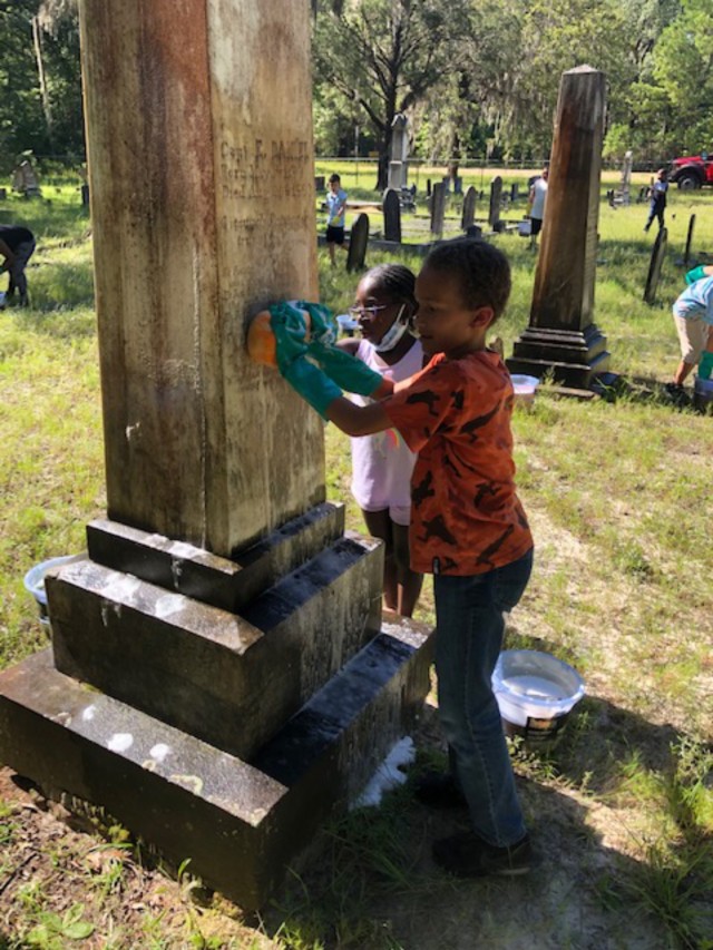 Children from the Youth Center assist in cleaning headstones during a cemetery cleanup event at Taylor’s Creek Cemetery. During the event, the children were given a brief historical tour and instructed on the proper care and cleaning of headstones. The event provided an opportunity to learn about civic responsibility, the installation&#39;s cultural resources, and the importance of protecting and preserving them for future generations.