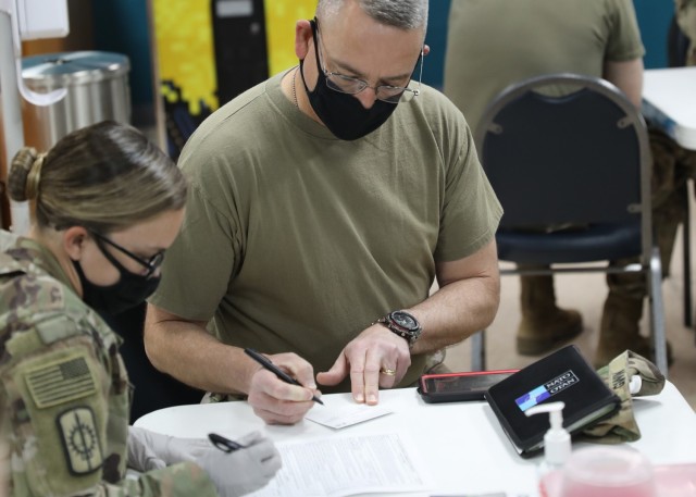 Army Reserve Command Sgt. Maj. Keith Gwin, deployed to Camp Arifjan, Kuwait, as the senior enlisted advisor to the deputy commanding general of 1st Theater Sustainment Command, reviews his paperwork before receiving the one-dose Janssen Biotech...