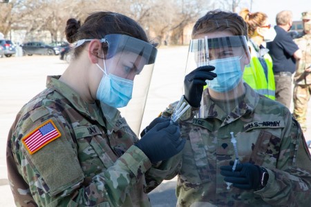 U.S. Army Spc. Haleigh Day (left) and Spc. Zoe Festge (right), 1st Battalion, 63rd Armored Regiment, 2nd Armor Brigade Combat Team, 1st Infantry Division, check the labels on the vaccine syringes at the Fair Park COVID-19 Community Vaccination Center in Dallas, Texas, Feb. 24, 2021. The Soldiers, deployed from Fort Riley, Kansas, support civilian medical personnel in administering COVID-19 vaccines. U.S. Northern Command, through U.S. Army North, remains committed to providing continued, flexible Department of Defense support to the Federal Emergency Management Agency as part of the whole-of-government response to COVID-19. (U.S. Army photo by Spc. Michael Ybarra, 5th Mobile Public Affairs Detachment)