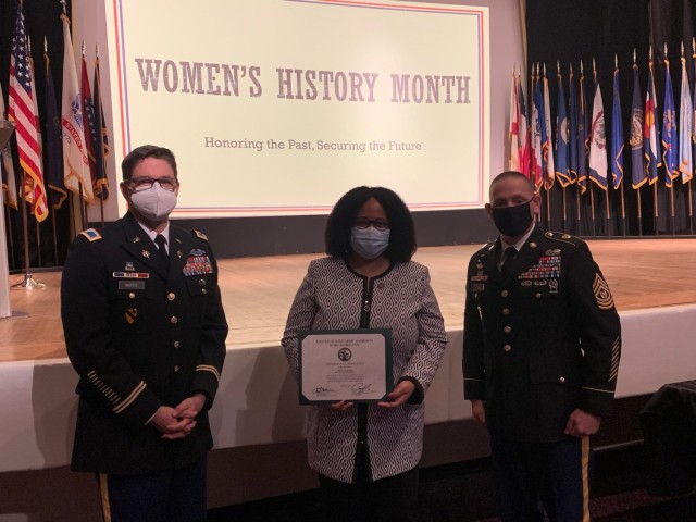 Col. Martin, Fort Hamilton Garrison Commander, and CSM Michael McCabe, present guest speaker, Assembly member Mathylde Frontus, with a token of appreciation during the Women’s History Month observance at the post theater on Fort Hamilton, N.Y., March 12. 2021. “New York State and specifically New York City has always been the center of the modern women’s rights movement which frankly allows all of us women to be sitting here today, especially someone like me that is daughter of immigrants, who is now a member of the N.Y. legislature,” Frontus said.  (U.S. Army photo)