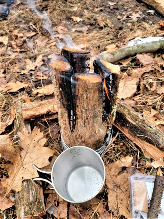 A coffee mug warms over a fire as students in Cold-Weather Operations Course class 21-05 conduct field training with improvised shelters March 16, 2021, at a training area at Fort McCoy, Wis. CWOC students are trained on a variety of cold-weather...
