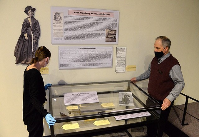 Fayelee Overman, museum technician, and Russell Ronspies, museum curator, replace a display case top while setting up the "19th Century Female Soldiers" exhibit March 11 at the Frontier Army Museum. The exhibit features information about women...