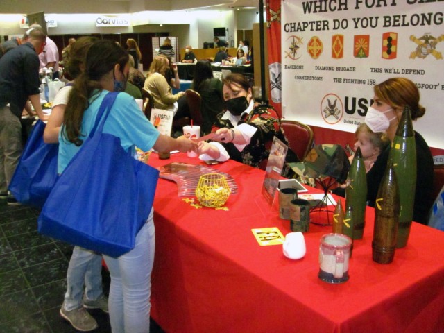 Girl Scouts, from left, Annabell Mosley, 12, and Jazmine Leggett, 11, pick up United States Field Artillery Association giveaway items from Rachal Smith. Smith and Kayla Walker, at right, holding daughter Bowen Walker, 2, represented the USFAA at...