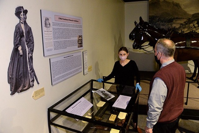 After arranging information placards and artifacts, Fayelee Overman, museum technician, shows Russell Ronspies, museum curator, the "19th Century Female Soldiers" exhibit for his approval March 11 at the Frontier Army Museum. The exhibit features...