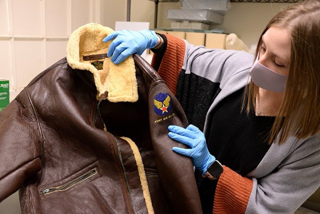 Fayelee Overman, museum technician, holds up a World War II-era Army Air Force mechanic's jacket as she explains its condition and the cleaning of corroded zippers that will need to be done before it can join other early aviation-related items in...