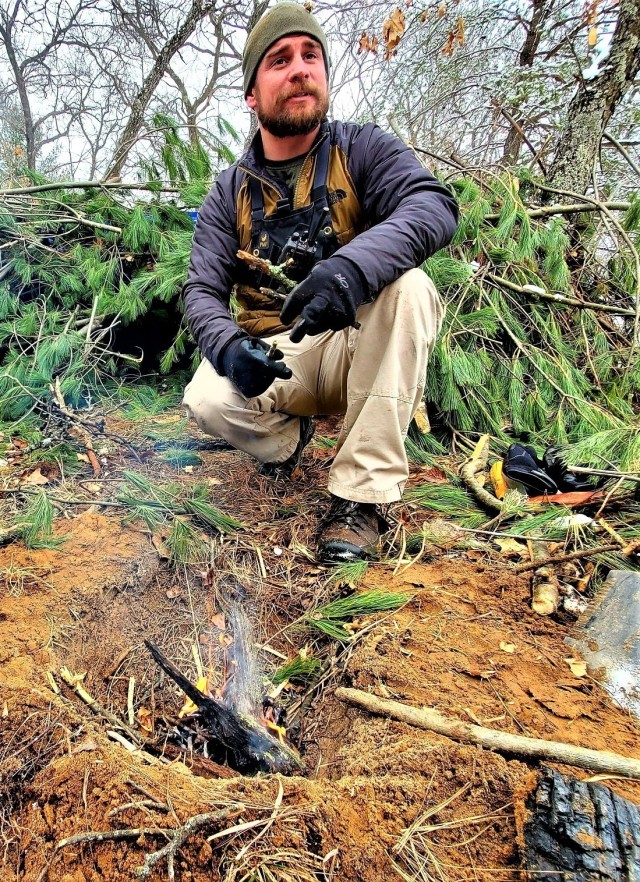Instructor Brian Seamann helps students in Cold-Weather Operations Course class 21-05 conduct field training with improvised shelters, including with the one shown here, March 16, 2021, at a training area at Fort McCoy, Wis. CWOC students are...