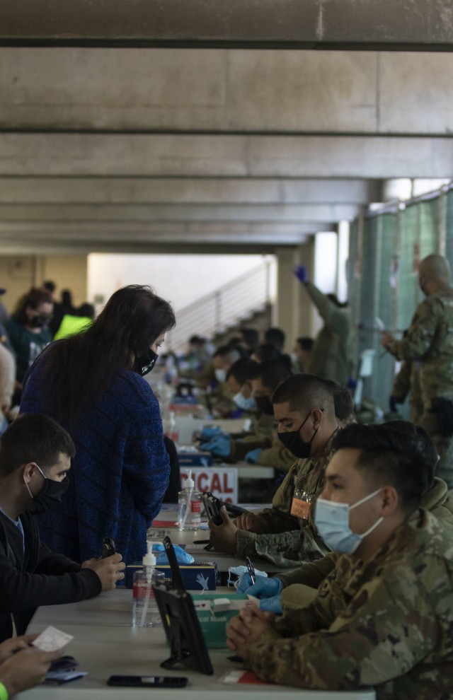 Service members with California’s Air National Guard process California community members before they receive their vaccination at the walk-up vaccination site at California State University Los Angeles in California, Feb. 20, 2021. U.S. Northern Command, through U.S. Army North, remains committed to providing continued, flexible Department of Defense support to the Federal Emergency Management Agency as part of the whole-of-government response to COVID-19. (U.S. Army photo by Pfc. Garrison Waites/5th Mobile Public Affairs Detachment)