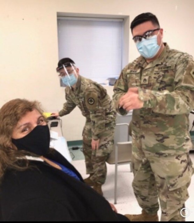 BOSTON -- Staff Sgt. David Bravo, a combat medic with the Massachusetts National Guard, vaccinates his mother at East Boston Neighborhood Health Center.  Bravo, who along with other Massachusetts National Guard members, has been activated by the...