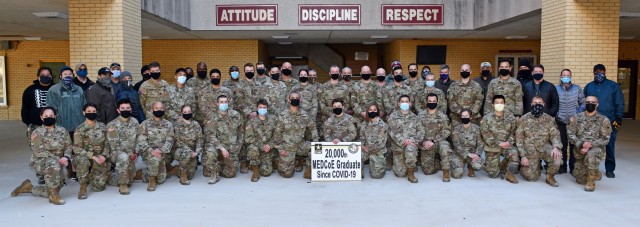 Sgt. Carter McCall in the center  holding the 20,000th MEDCoE graduate since COVID-19 sign along with his classmates and course cadre.