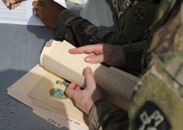 A volunteer leafs through Norwegian Foot March certificates after the March 21, 2021 recognition ceremony for the 328 U.S and coalition military personnel, who completed the NFM at Camp Arifjan, Kuwait. The Norwegian Army instituted the NFM in 1915, and the 18.6-mile with a 25-pound ruck completed under the age-group time limit event has become a tradition in the U.S. military, too. (U.S. Army photo by Staff Sgt. Neil W. McCabe)