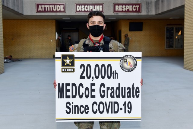 Sgt. Carter McCall holding a sign as the 20,000th MEDCoE graduate since COVID-19.