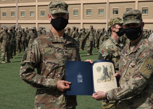 Army Reserve Col. Garrett Kolo, 310th Sustainment Command (Expeditionary), holds his Norwegian Foot March certificate presented to him by Army Reserve Brig. Gen. Justin Swanson, the commanding general of the 310th ESC, at the March 21, 2021 recognition ceremony at Camp Arifjan, Kuwait. Kolo, was the top finisher in the NFM when he crossed the finish line completing the 18.6-mile course with a 25-pound ruck in 2 hours and 52 minutes. (U.S. Army photo by Staff Sgt. Neil W. McCabe)