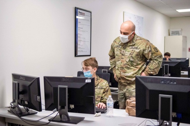 Sgt. Chris Marra, instructor for the Information Technology Training Center (ITTC), National Guard Professional Education Center, observes Pvt. Jeffery Abbot, an RSP recruit awaiting basic training, during the Interactive War Games cyber...
