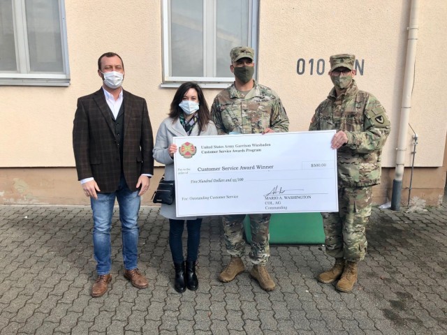 WIESBADEN, Germany -- Julie A. Kelly, education services specialist, receives her check from Col. Mario Washington, garrison commander, Command Sgt. Maj. Christopher Truchon and Scott Mowry, deputy to the garrison commander, for outstanding...