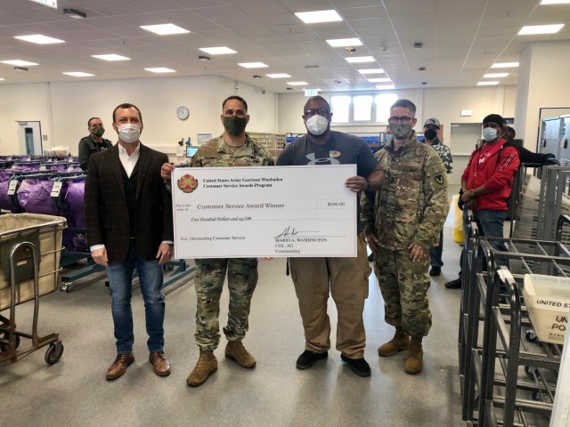 WIESBADEN, Germany -- Michael Ewings, postal operations assistant, receives his check from Col. Mario Washington, garrison commander, Command Sgt. Maj. Christopher Truchon and Scott Mowry, deputy to the garrison commander, for outstanding customer...