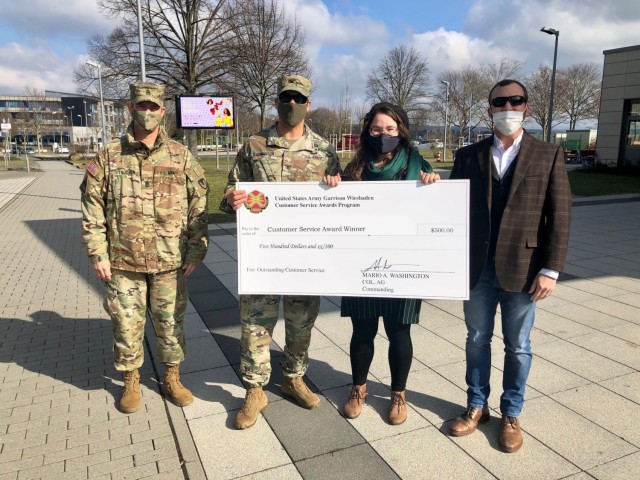 WIESBADEN, Germany -- Katrina Pennington, bartender, receives her check from Col. Mario Washington, garrison commander, Command Sgt. Maj. Christopher Truchon and Scott Mowry, deputy to the garrison commander, for outstanding customer service at...