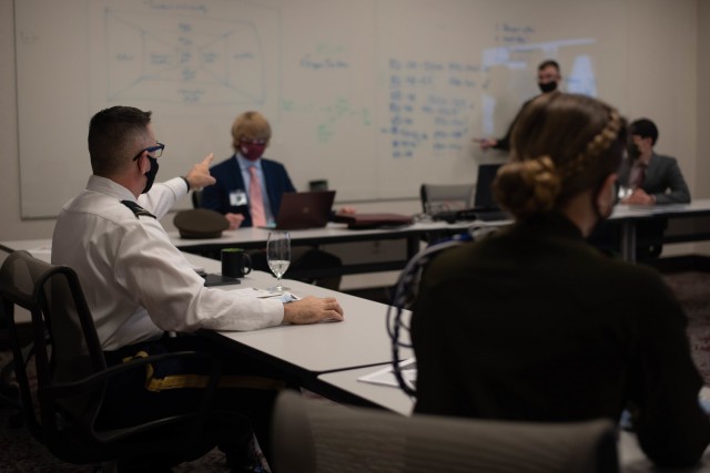 Texas A&M graduate and program facilitator, Col. M. Straus Scantlin, Director, Strategic Initiatives Group (SIG), U.S. Army Civil Affairs and Psychological Operations Command (Airborne) works with his team during their discussions as the delegates...