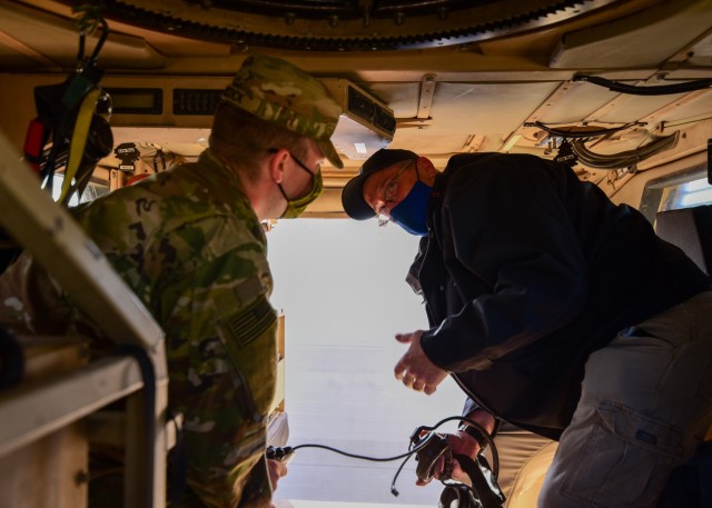 Brian L. Debutts, logistics assistance representative, 401st Army Field Support Brigade, advises Sgt. Tommy D. Riddick, U.S. Army Signal Support Systems specialist, on the proper operation of a Single Channel Ground and Airborne Radio System/...