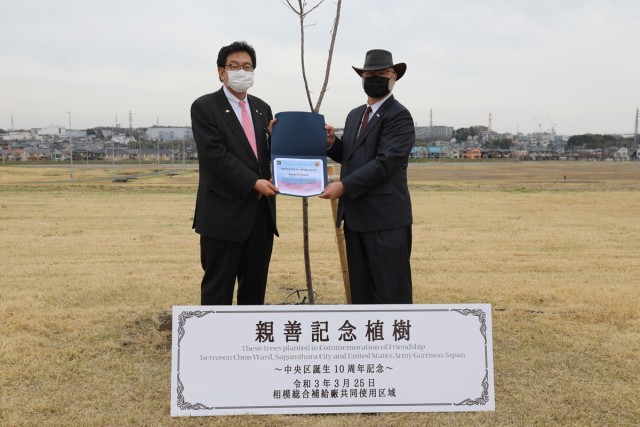Sagamihara Chuo Ward Director Masayuki Fujita, left, and Kenneth Estabrook, right, assigned to the Directorate of Public Works and the chief Sagami sub-facility engineer, pose for a photo in front of a cherry blossom tree they planted together...