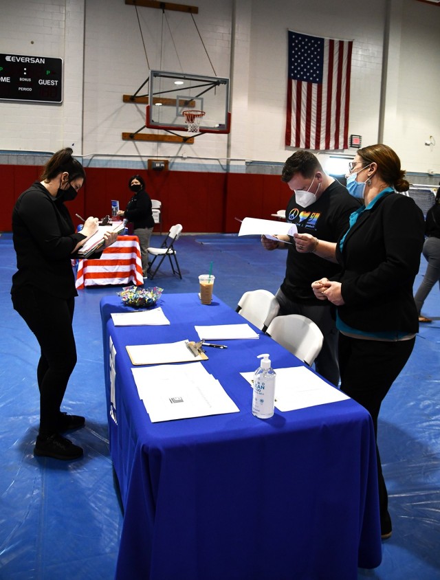 Alizabeth Cannon (left), a military dependent, fills out an application to work at Goodwill as Paul Dunham (middle), Goodwill donation service attendant, and Victoria Sitting, Goodwill assistant manager, stand ready to answer questions.
