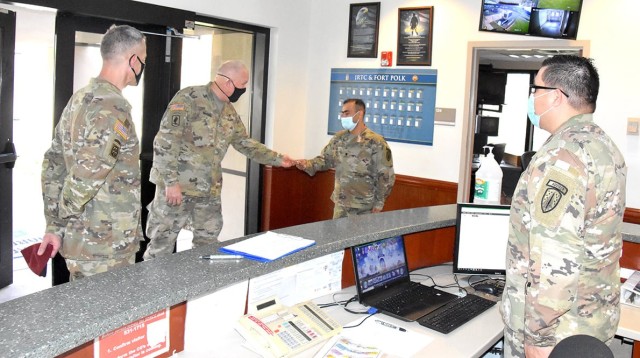 Maj. Gen. Timothy P. McGuire (second from left), IMCOM deputy commander, presents a coin to Spc. Yaser Ali, 52nd Translator Interpreter Company as Brig. Gen. David S. Doyle, (left) commander, JRTC and Fort Polk, looks on March 23.