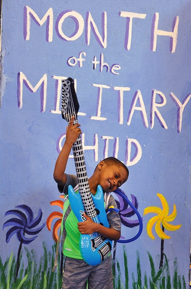 Six-year-old Jonathan Baptiste jams on an inflatable guitar while his mother, Maj. Mona Baptiste, Academic and Technology Support Directorate, Command and General Staff College, takes a video of his performance at a prop photo booth at the Children's Festival April 8, 2017, at Harney Sports Complex. April is Month of the Military Child. File photo by Prudence Siebert/Fort Leavenworth Lamp
