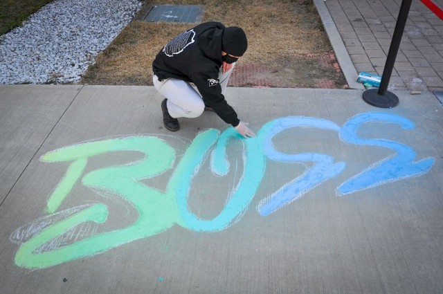 CAMP HUMPHREYS, Republic of Korea - Spc. Ian Holmes, the Humphreys Better Opportunities for Single Soldiers (BOSS) President and a CH-47 helicopter repairer assigned to Installation Management Command, adds the finishing touches to the BOSS logo created as part of their Chalk-Off event, Dec. 4, 2020. The BOSS program organizes and hosts a variety of events and programs designed to help build morale and foster a greater sense of community for single and unaccompanied Soldiers at Humphreys. (Courtesy photo provided by Spc. Ian Holmes)
