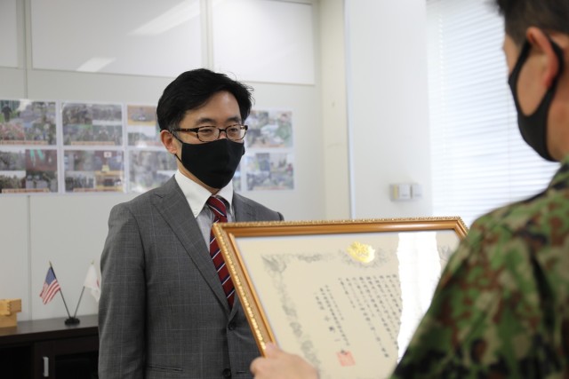 Toshiyuki Ito, left, assigned to the U.S. Army Garrison Japan Public Affairs Office, receives a certificate of appreciation from Col. Kazuya Ono, commander of the JGSDF’s 4th Engineer Group and JGSDF Camp Zama during a March 30 ceremony on Camp...