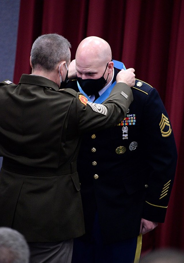 Combined Arms Center Command Sgt. Maj. Eric Dostie places the Sergeant Audie Murphy Club medallion around the neck of Sgt. 1st Class Chad Hickey, 291st Military Police Company, 40th MP Battalion (Detention), during the SAMC induction ceremony for...
