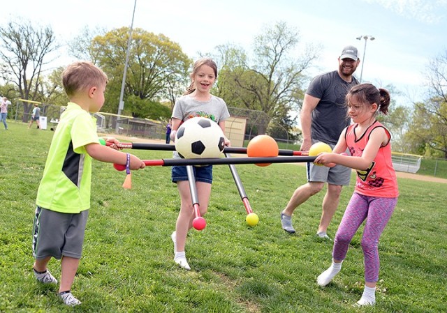 Dad Loren Schmidt watches 4-year-old Riley, 9-year-old Evelyn and 6-year-old Danica balance sports balls as they make their way toward a relay finish line where mom Air National Guard Maj. Angie Schmidt, Command and General Staff Officer Course...