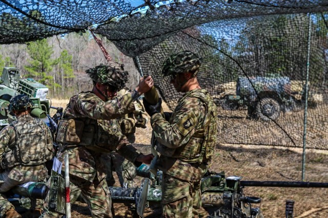 U.S. Army Pvt. Koby Smith, cannon crewmember, from A Battery “Automatic”, 2nd Battalion, 32nd Field Artillery Regiment “Proud Americans,” 1st Brigade Combat Team “Bastogne”, 101st Airborne Division (Air Assault), right, gives Staff...