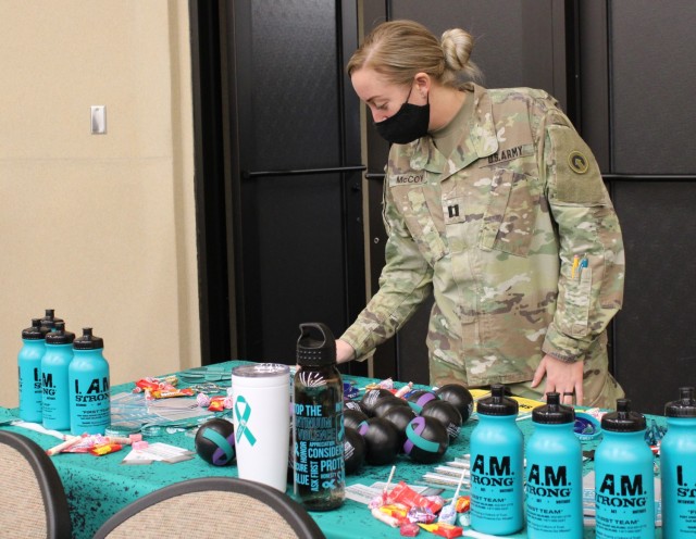 Capt. Nicole McCoy,  Sexual Harassment/Assault Response and Prevention program manager, 1st Theater Sustainment Command, sets up a table with free SHARP gear and information at the Sexual Assault Awareness and Prevention Month kick off event at Olive Theater March 29, 2021 at Fort Knox, Kentucky.