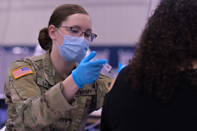 U.S. Army Spc. Emily Salmon, 2123 Forward Support Company combat medic administers the COVID-19 vaccination in the South Suburban College gym, South Holland, Illinois, February 25, 2021. State guard members were called upon to provide support for the COVID-19 relief efforts and administering the vaccine. (U.S. National Guard photo by Staff Sgt. Aaron Rodriguez)