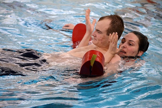 Red Cross lifeguard certification class instructor Thula Stenerson, head lifeguard with Family and Morale, Welfare and Recreation, demonstrates a rescue with "victim" Weston Marshall, lead Fort Leavenworth lifeguard, during lifeguard training...