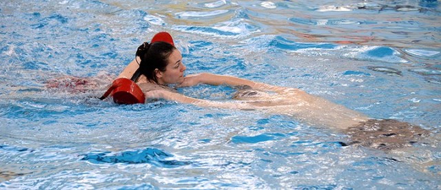 Red Cross lifeguard certification class instructor Thula Stenerson, head lifeguard with Family and Morale, Welfare and Recreation, demonstrates a rescue with "victim" Weston Marshall, lead Fort Leavenworth lifeguard, during lifeguard training...