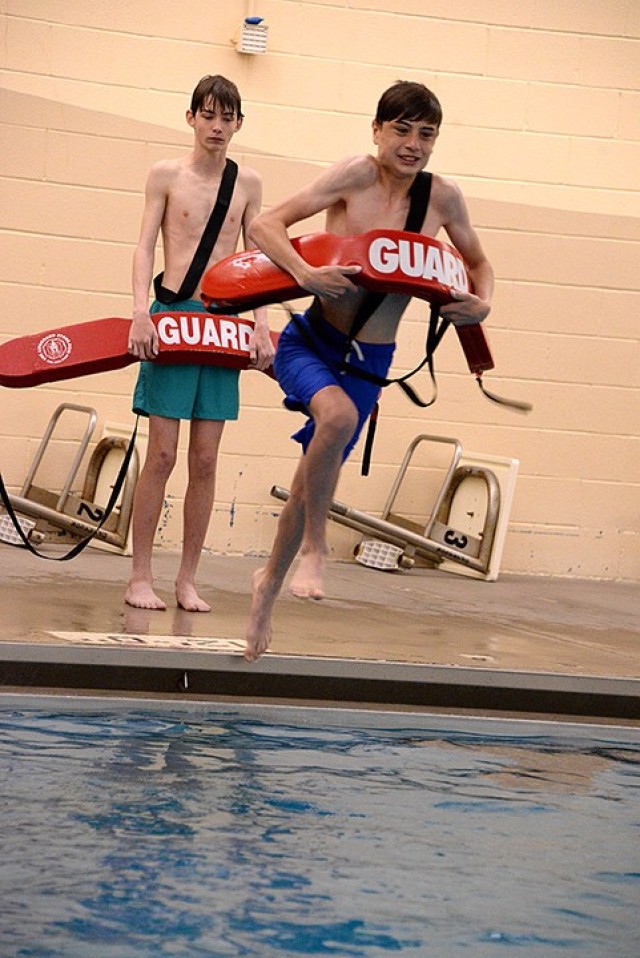 Karter Watson watches as Jonathan Purvis leaps from the edge of the pool to practice rescuing a "victim" flailing in the water during lifeguard training April 3 at Harney Pool. Photo by Prudence Siebert/Fort Leavenworth Lamp