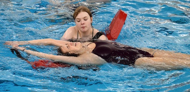 Kate Brooks uses momentum to pull Ashley Morgan onto a lifeguard rescue tube during lifeguard training April 3 at Harney Pool. Lifeguard training students took turns practicing rescues and portraying victims. Photo by Prudence Siebert/Fort...