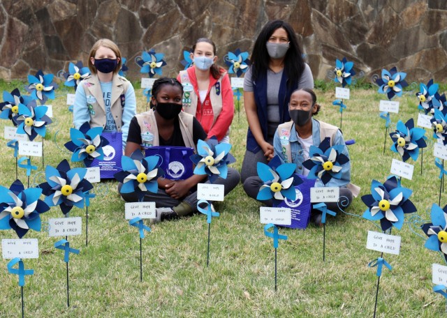 From left, Kaitlyn Dodson, 12; Madison Swanigan, 13; Jane Dalton, 12; and Naomi Thomas, 14, members of Girl Scout Troop 600, pose for a photo with their troop leader, Valerie Thomas, after planting pinwheels in honor of National Child Abuse...
