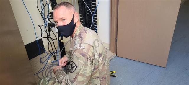 Sgt. 1st Class Brandon Whitehall improves a communications room for efficiencies and maintainability in support of TF-West/DCE-West at Santa Rita, Guam.