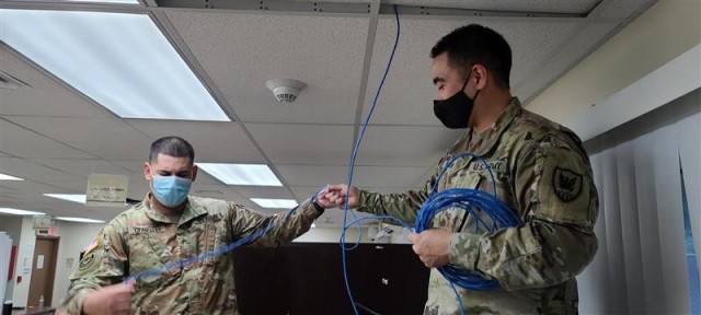 Sgt. Derik Gonzales(left) and Staff Sgt. Dane Kaneakua (right), run network cables in Santa Rita, Guam in support of Contingency Command Post operations.