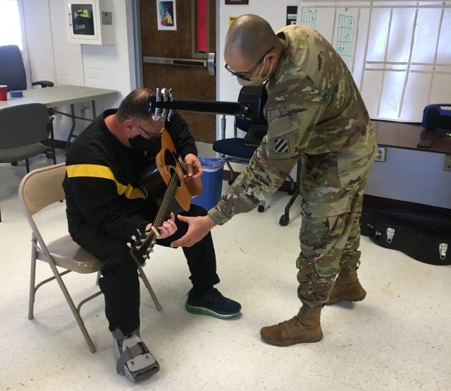 Spc. Jonathan Rodriquez teaches Lt. Col. Ken Sanders during a music lesson as part of the Adaptive Reconditioning Program. The 3rd Infantry Division Band provides volunteers to assist with an eight-week long Adaptive Reconditioning Program to teach guitar as part of recreational therapy. Photo by Sgt. Anthony Licata 